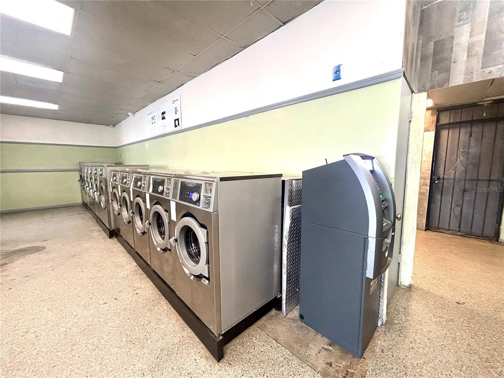 A row of stainless steel laundry machines sits next to an ATM in a room — 2604 AVENUE V NW, WINTER HAVEN, FL