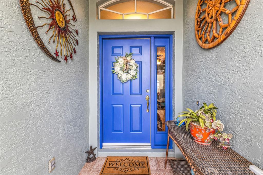 A bright blue front door with a wreath sits under a transom window — 1693 PALACE COURT, PUNTA GORDA, FL