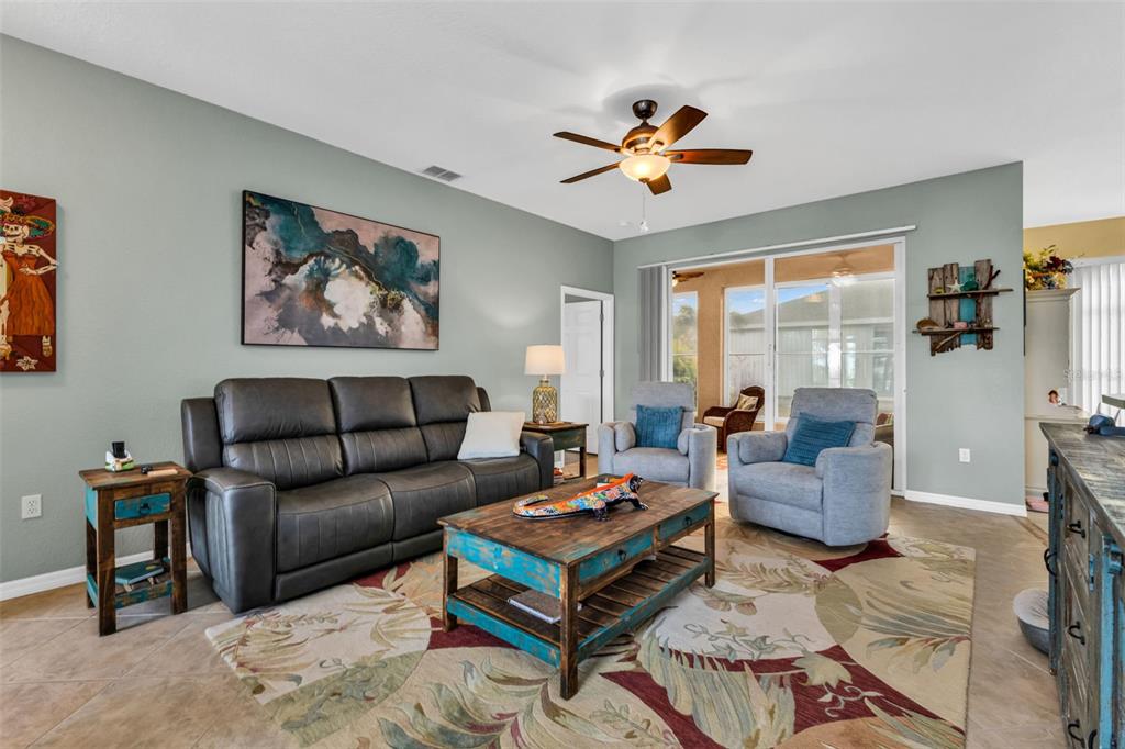 A living room features a dark leather sofa, two armchairs, and a rustic wooden coffee table — 1693 PALACE COURT, PUNTA GORDA, FL