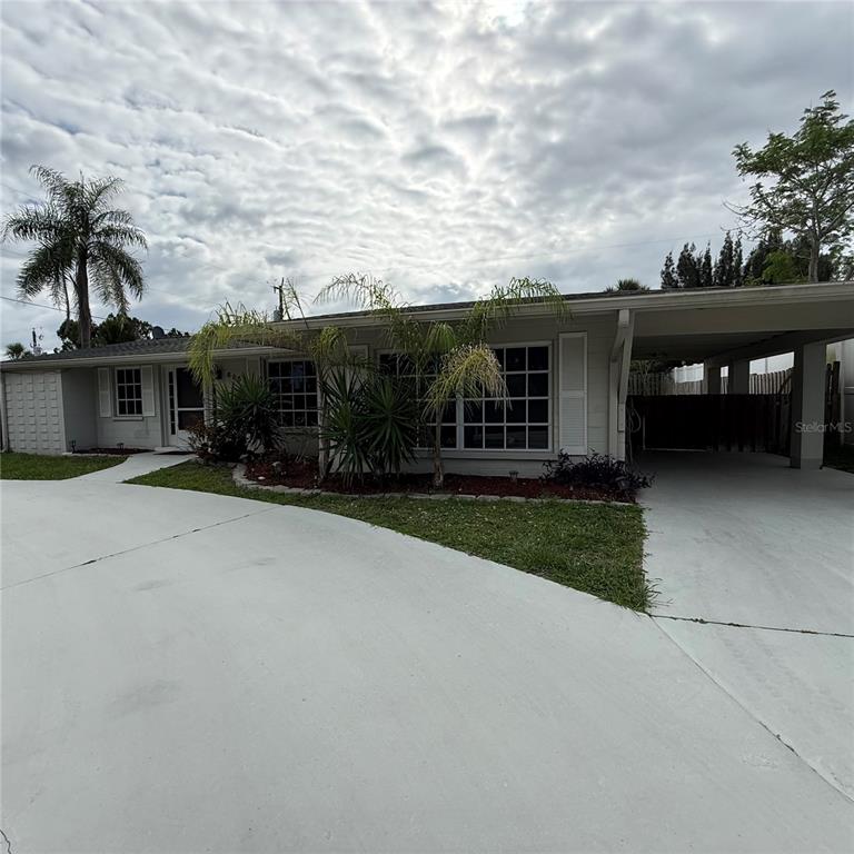 A single-story house with a concrete driveway, a carport, and a palm tree in front — 695 ALLIGATOR DRIVE, VENICE, FL