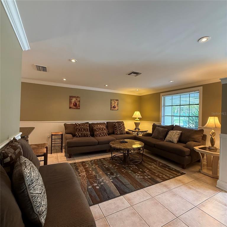 A living room features brown sofas, a patterned area rug, and tile flooring — 695 ALLIGATOR DRIVE, VENICE, FL
