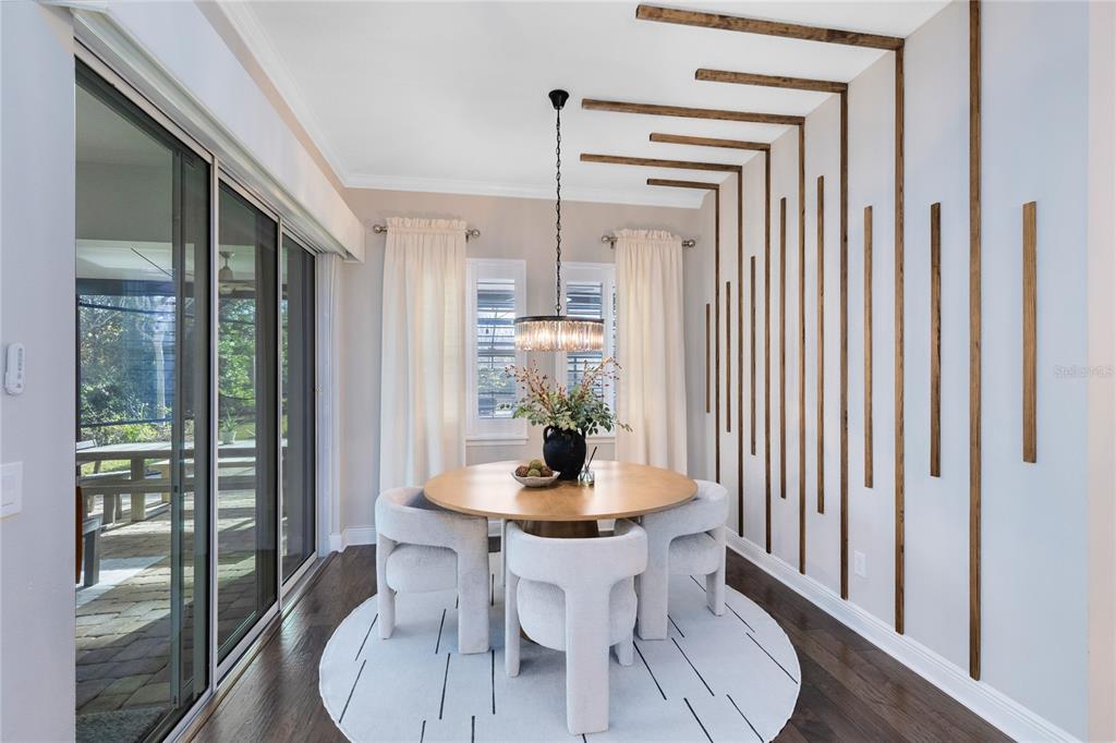A dining room features a round table, upholstered chairs, and a decorative wood-slat wall feature — 9374 REYMONT STREET, ORLANDO, FL