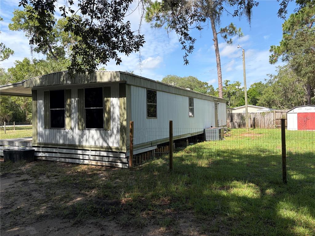 An exterior view of a single-wide mobile home with white siding and a fenced yard — 6785 W COUNTRY CLUB DRIVE, HOMOSASSA, FL