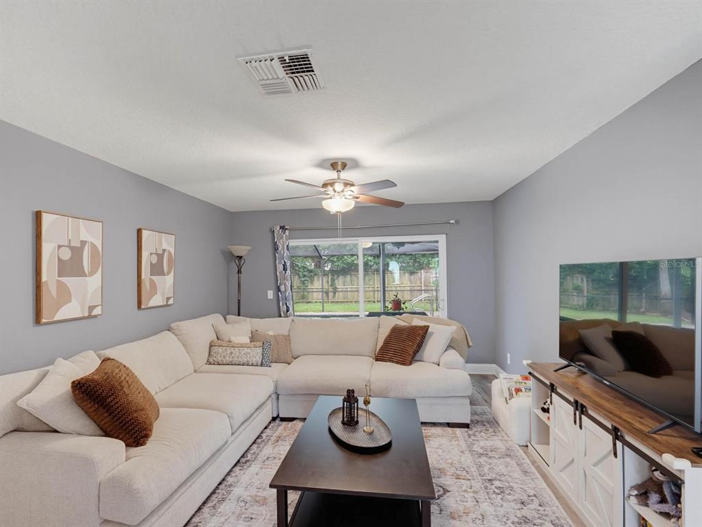 A living room features a large sectional sofa, a coffee table, and a television console — 2988 PINEWOOD RUN, PALM HARBOR, FL