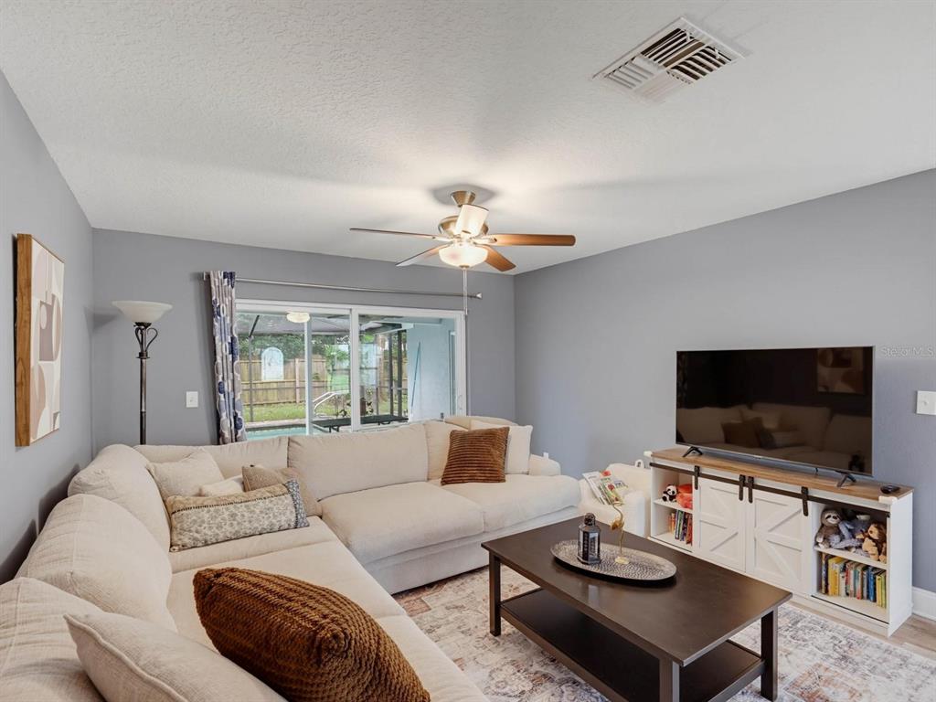 A living room features a large sectional sofa, a coffee table, and a television console — 2988 PINEWOOD RUN, PALM HARBOR, FL