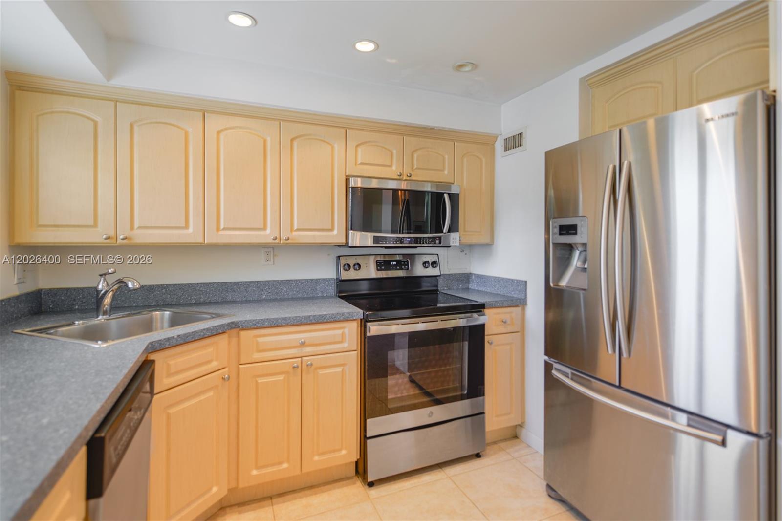 A kitchen features light wood cabinets, stainless steel appliances, and gray speckled countertops — 7720 SW 54th Ct # D, Miami FL 33143, MIAMI, FL