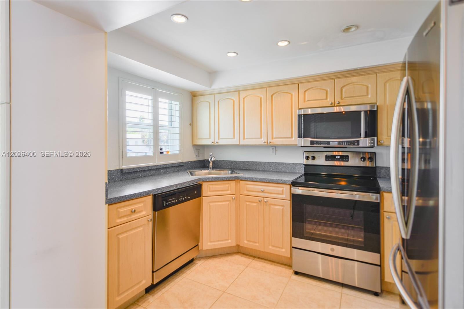 A kitchen features light wood cabinets, stainless steel appliances, and dark gray countertops — 7720 SW 54th Ct # D, Miami FL 33143, MIAMI, FL