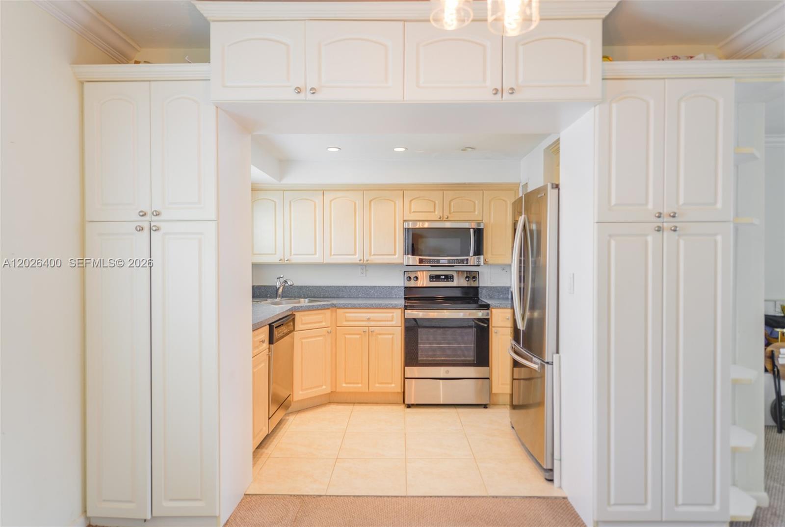 A kitchen features light wood cabinets, stainless steel appliances, and a tiled floor — 7720 SW 54th Ct # D, Miami FL 33143, MIAMI, FL