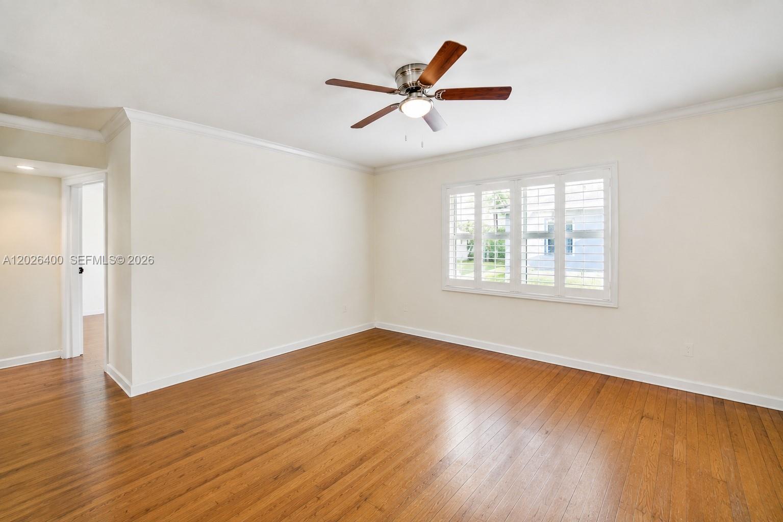 An empty room features hardwood floors, white walls, crown molding, and a ceiling fan — 7720 SW 54th Ct # D, Miami FL 33143, MIAMI, FL