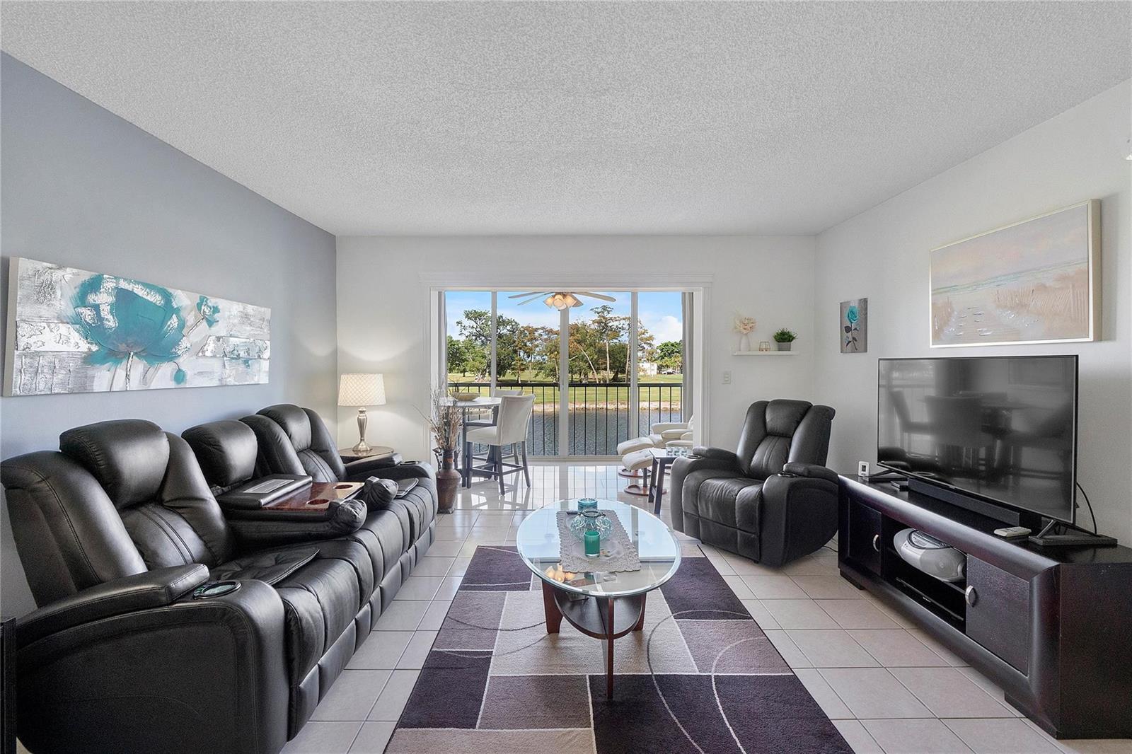 A living room features a black leather sofa, a recliner, and a sliding glass door view — 7807 Golf Circle Drive # 211, Margate FL 33063, MARGATE, FL