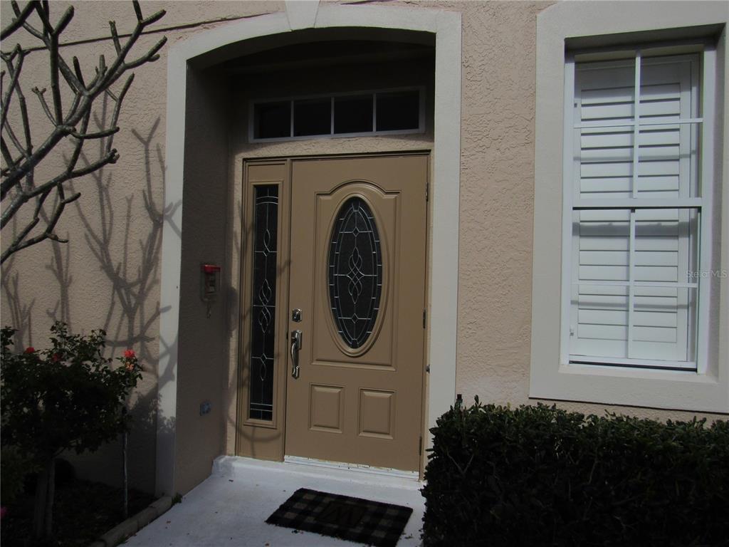 The exterior entrance features a tan front door with an oval glass insert and sidelight — 4012 DEBERRY DRIVE, SARASOTA, FL
