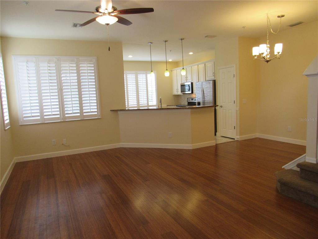 An open-concept living area features hardwood floors, a kitchen with white cabinets, and a breakfast bar — 4012 DEBERRY DRIVE, SARASOTA, FL