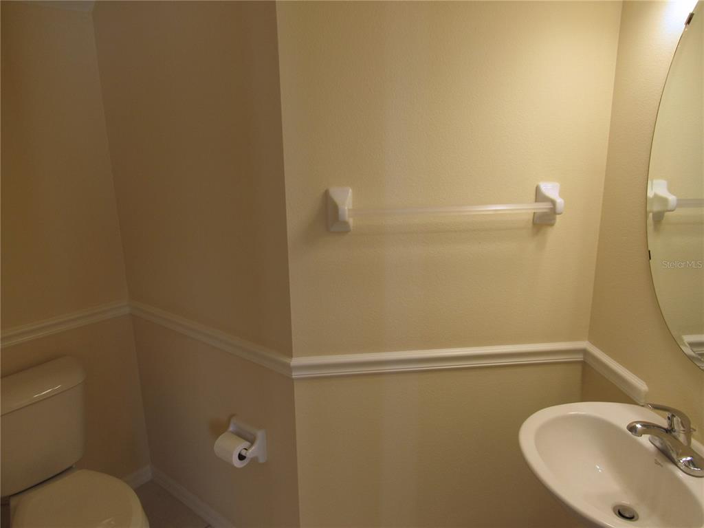 A small bathroom features a toilet, a pedestal sink, and a wall-mounted towel bar — 4012 DEBERRY DRIVE, SARASOTA, FL