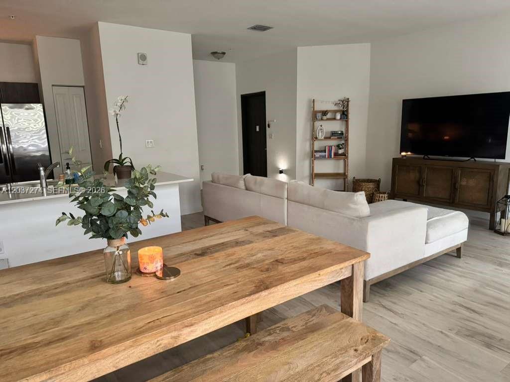 A dining area with a wooden table and bench overlooks a living room with a sofa — 15540 SW 136th St # 101, Miami FL 33196, MIAMI, FL
