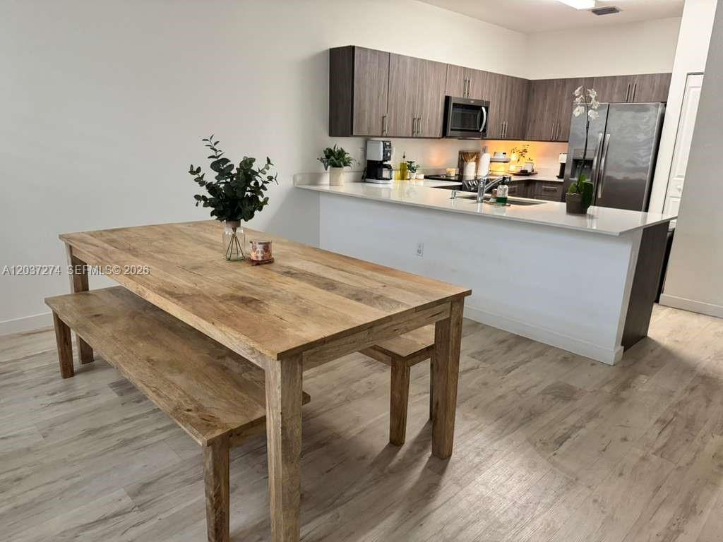A kitchen with dark wood cabinets and a white island sits beside a wooden dining table — 15540 SW 136th St # 101, Miami FL 33196, MIAMI, FL