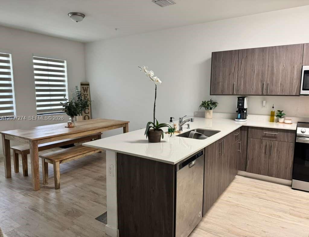 A kitchen with dark wood cabinets, white countertops, and an adjacent wooden dining table — 15540 SW 136th St # 101, Miami FL 33196, MIAMI, FL