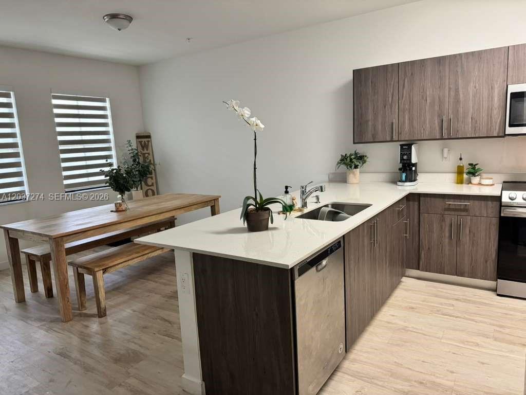 A modern kitchen features dark wood cabinets, white countertops, and an adjacent dining area — 15540 SW 136th St # 101, Miami FL 33196, MIAMI, FL