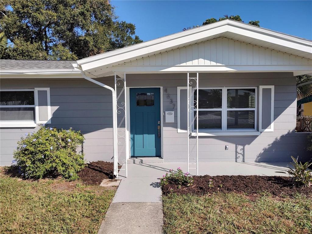 A gray house exterior features a teal front door, white trim, and decorative metal porch supports — 4637 12TH AVENUE N, ST PETERSBURG, FL