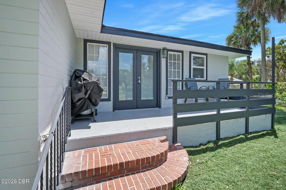 A patio with a brick step, a black railing, and double glass doors — 419 BURLEIGH AVENUE, HOLLY HILL, FL