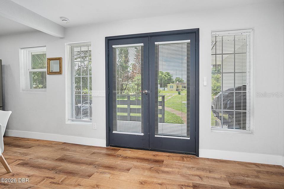 A room with light-colored walls, wood-look flooring, a dark double door, and windows with blinds — 419 BURLEIGH AVENUE, HOLLY HILL, FL