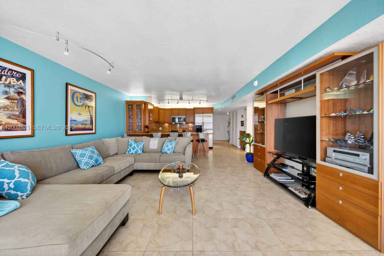A living room with a sectional sofa, tile floors, and an open kitchen with bar seating — 6423 Collins Ave # 1204, Miami Beach FL 33141, MIAMI BEACH, FL