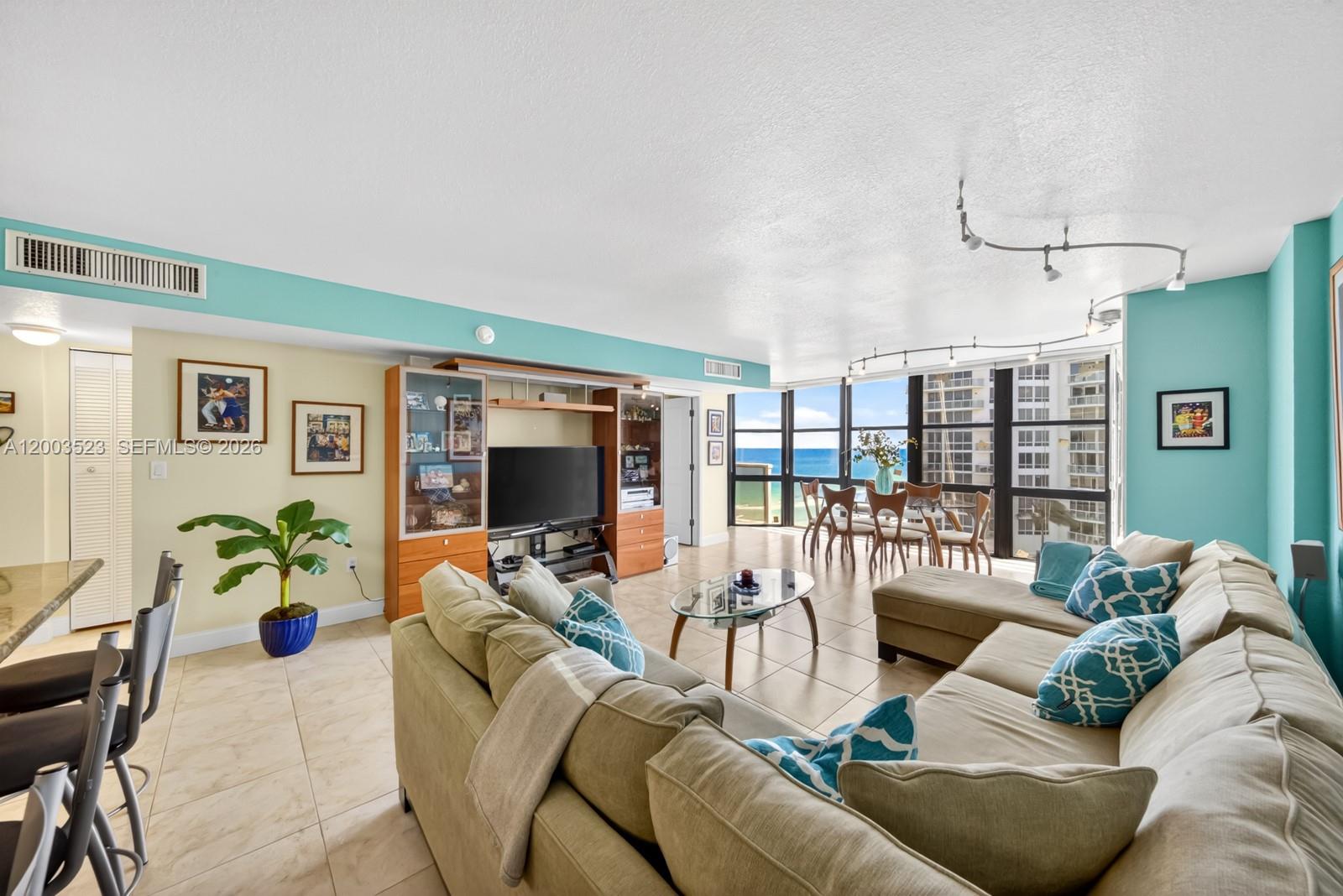 A living room with a sectional sofa, dining area, and floor-to-ceiling windows overlooking the ocean — 6423 Collins Ave # 1204, Miami Beach FL 33141, MIAMI BEACH, FL