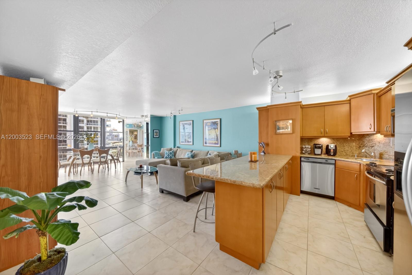 An open-concept living area features a kitchen with wood cabinets and a dining space — 6423 Collins Ave # 1204, Miami Beach FL 33141, MIAMI BEACH, FL