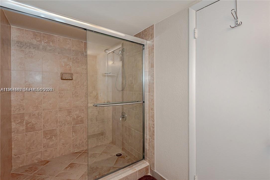 A walk-in shower with glass doors and beige tile walls is next to a door — 2304 NE 7th St # 27, Hallandale Beach FL 33009, HALLANDALE BEACH, FL