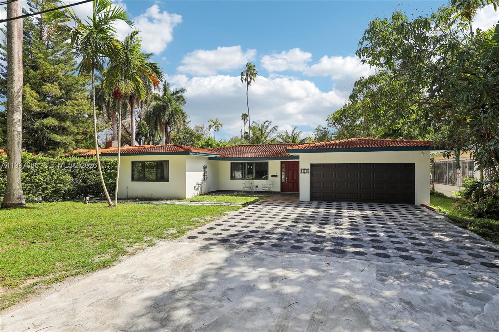 A single-story house with a tiled roof, a dark garage door, and a patterned driveway — 314 NE 85th St, El Portal FL 33138, EL PORTAL, FL