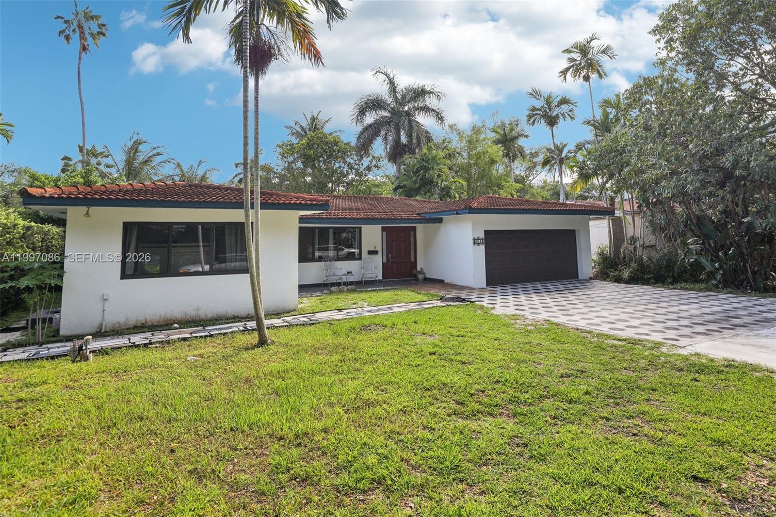 A single-story house with a white exterior, red tile roof, and a patterned driveway — 314 NE 85th St, El Portal FL 33138, EL PORTAL, FL