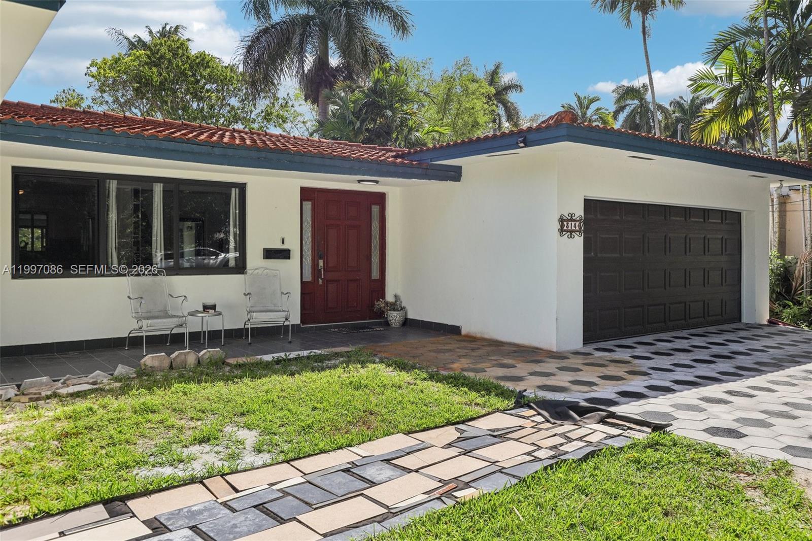 A single-story house with a white exterior, red tile roof, and a dark garage door — 314 NE 85th St, El Portal FL 33138, EL PORTAL, FL