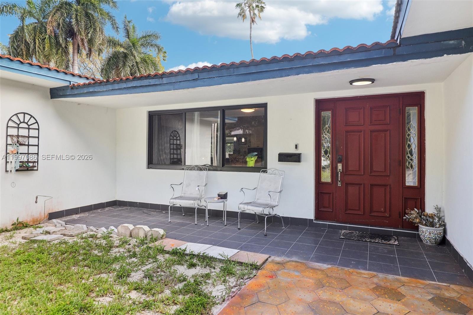 A front patio with tiled flooring, two metal chairs, and a red double front door — 314 NE 85th St, El Portal FL 33138, EL PORTAL, FL