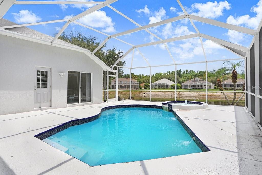 A swimming pool and spa are enclosed within a screened lanai overlooking a pond — 10227 QUAILS LANDING AVENUE, TAMPA, FL