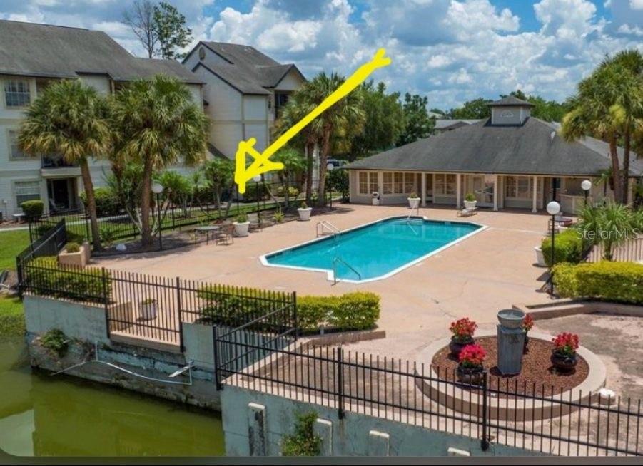 An outdoor swimming pool area with a surrounding patio, landscaping, and a nearby apartment building — 1908 LAKE ATRIUMS CIRCLE UNIT 14, ORLANDO, FL