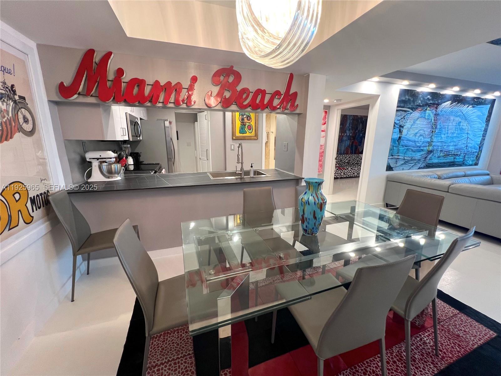 A dining area features a glass table, gray chairs, and a kitchen pass-through window — 650 West Ave # 2804, Miami Beach FL 33139, MIAMI BEACH, FL