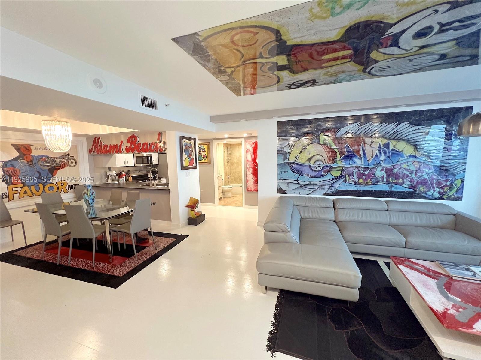 An open-concept living and dining area features white floors, modern furniture, and large wall art — 650 West Ave # 2804, Miami Beach FL 33139, MIAMI BEACH, FL