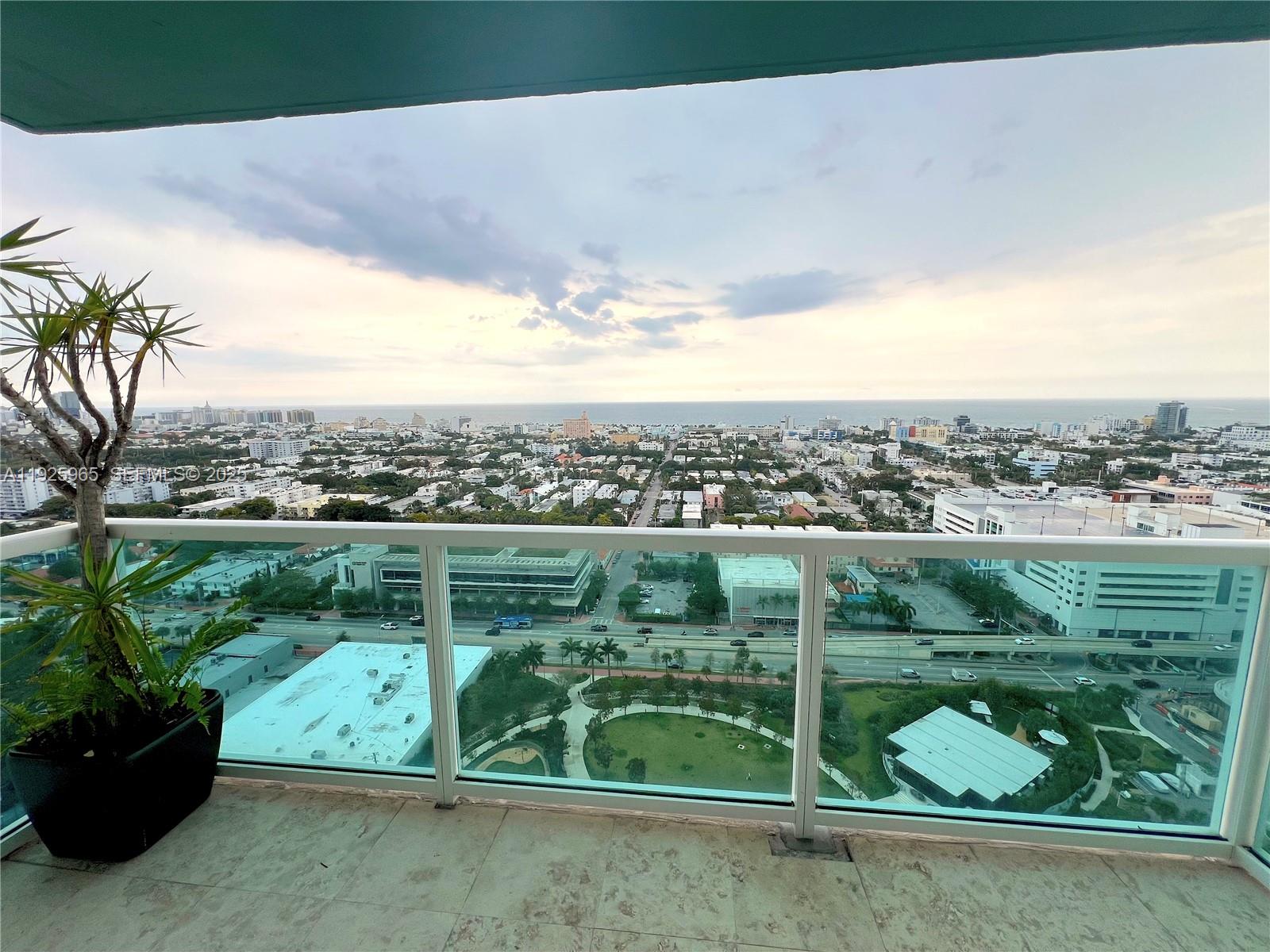 A high-rise balcony with a glass railing overlooks a city park and the ocean — 650 West Ave # 2804, Miami Beach FL 33139, MIAMI BEACH, FL