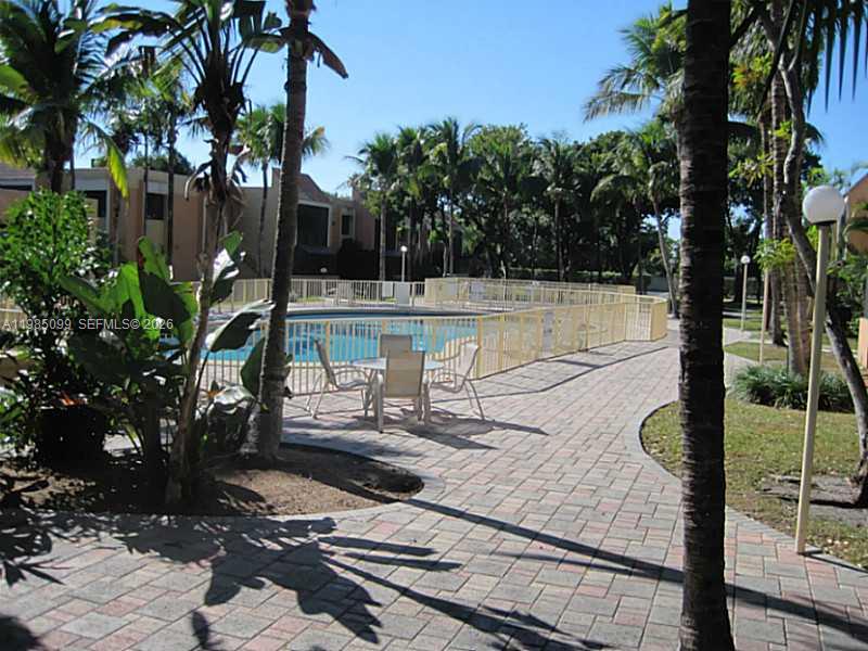 A paved patio area features a small table and chairs beside a fenced swimming pool — 7913 SW 104th St # G, Miami FL 33156, MIAMI, FL