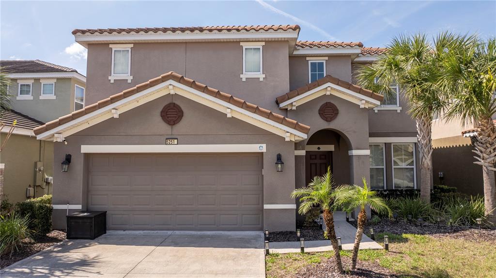 A two-story suburban house features a tan stucco exterior, a tiled roof, and a garage — 5251 WILDWOOD WAY, DAVENPORT, FL