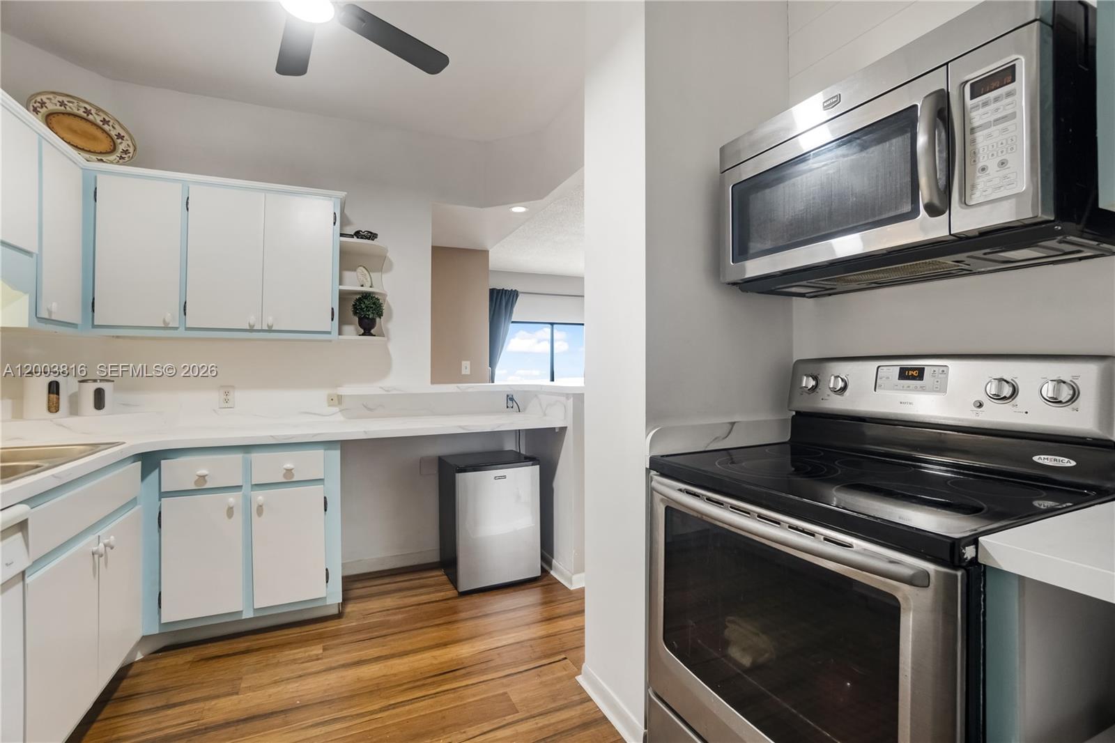 A kitchen features white cabinets with blue trim, stainless steel appliances, and wood flooring — 4330 Hillcrest Dr # 1017, Hollywood FL 33021, HOLLYWOOD, FL