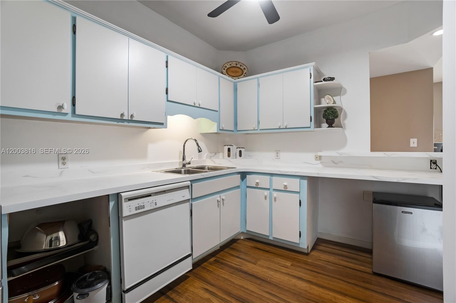 A kitchen features white cabinets with light blue trim, white countertops, and wood flooring — 4330 Hillcrest Dr # 1017, Hollywood FL 33021, HOLLYWOOD, FL