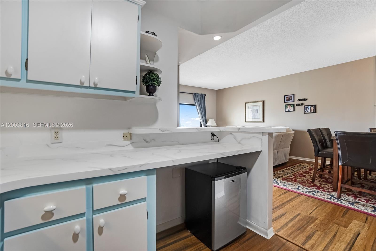 A kitchen counter with a mini-fridge overlooks a dining area with wood flooring — 4330 Hillcrest Dr # 1017, Hollywood FL 33021, HOLLYWOOD, FL