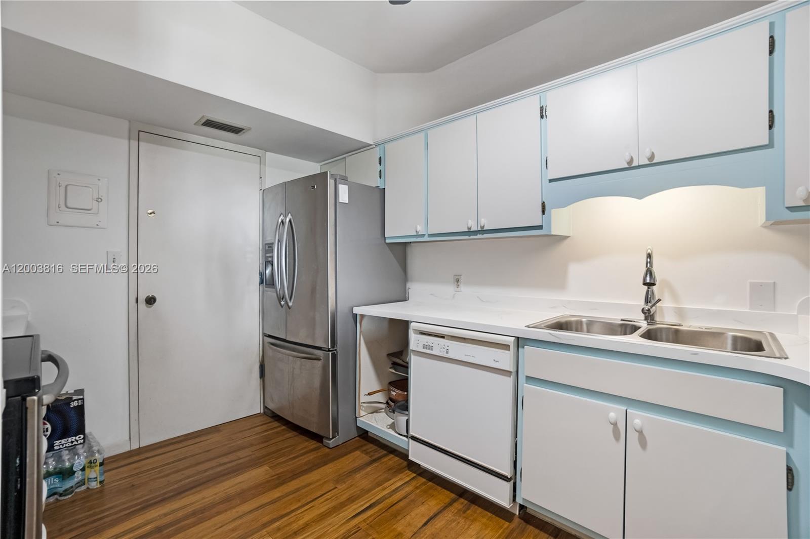 A kitchen features white cabinets with blue trim, stainless steel appliances, and wood flooring — 4330 Hillcrest Dr # 1017, Hollywood FL 33021, HOLLYWOOD, FL