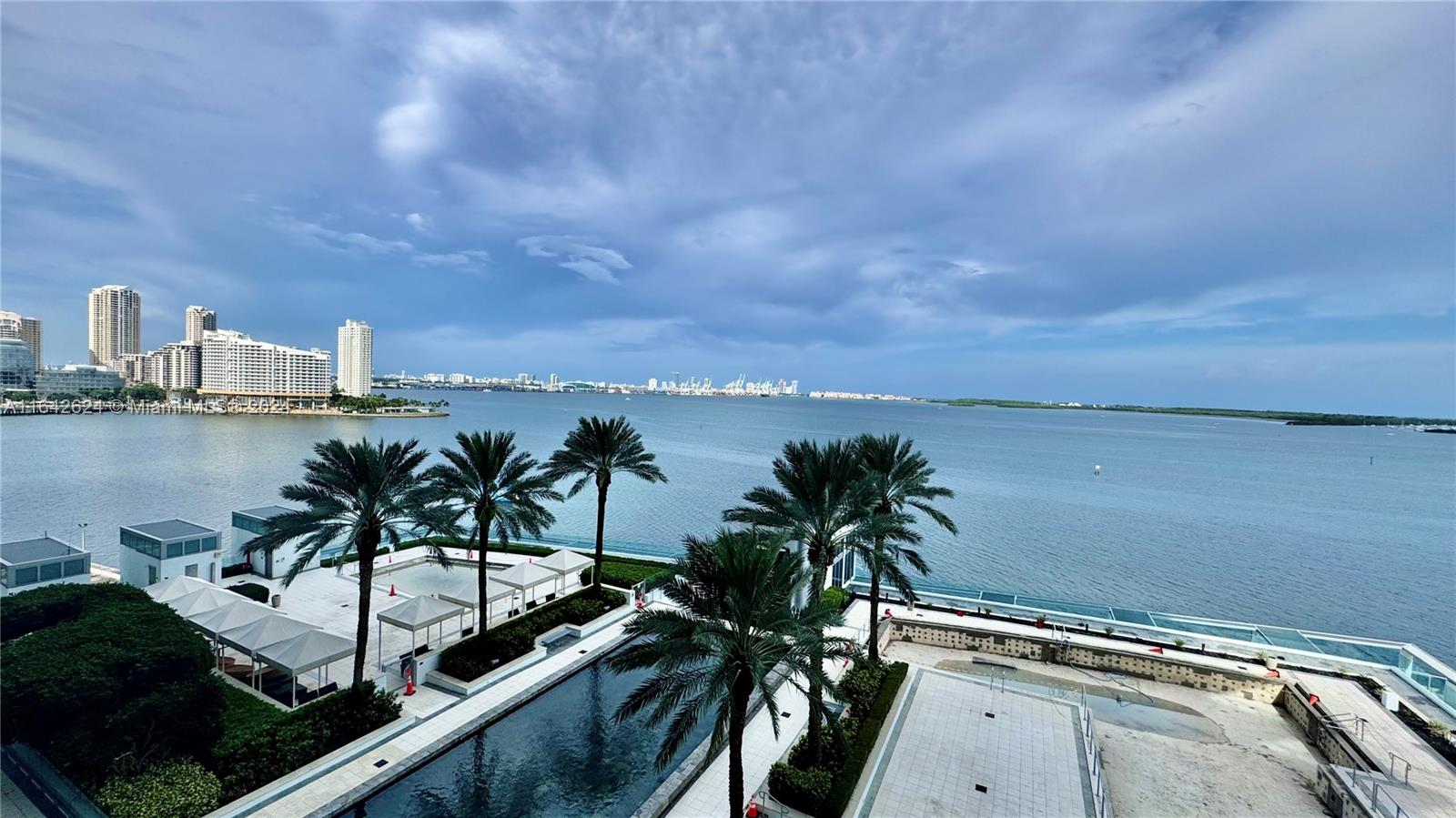 An elevated view of a swimming pool deck with palm trees overlooking a large bay — 1331 Brickell Bay Dr # 1109, Miami FL 33131, MIAMI, FL