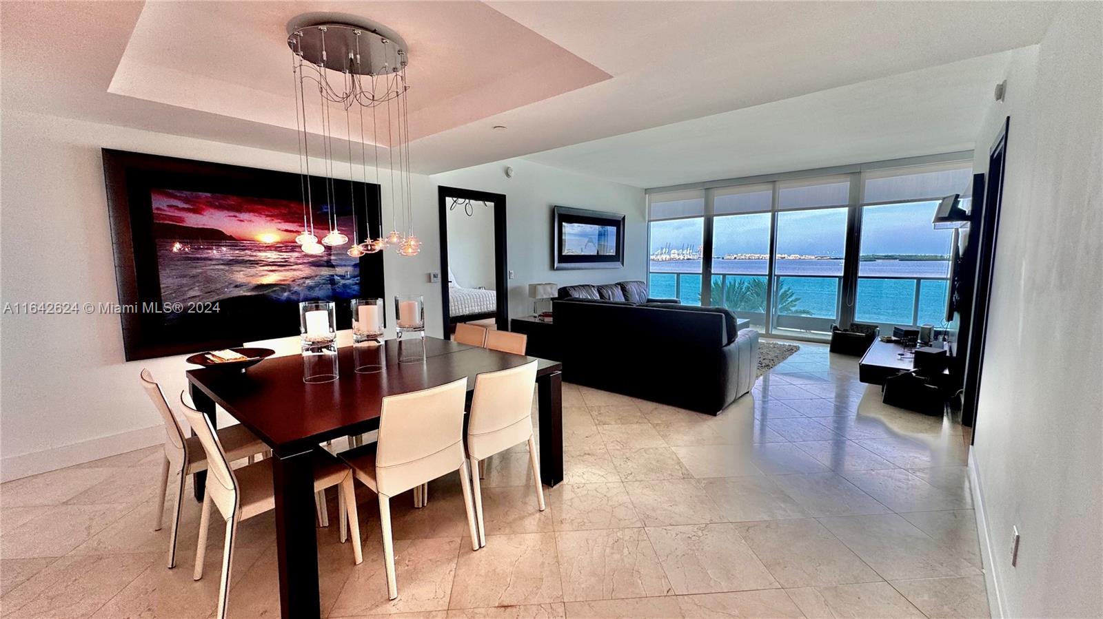 A dining area and living room with tile floors overlook the ocean through floor-to-ceiling windows — 1331 Brickell Bay Dr # 1109, Miami FL 33131, MIAMI, FL