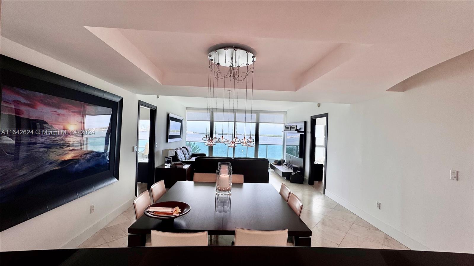 A dining area with a dark table and modern chandelier opens to a living room — 1331 Brickell Bay Dr # 1109, Miami FL 33131, MIAMI, FL