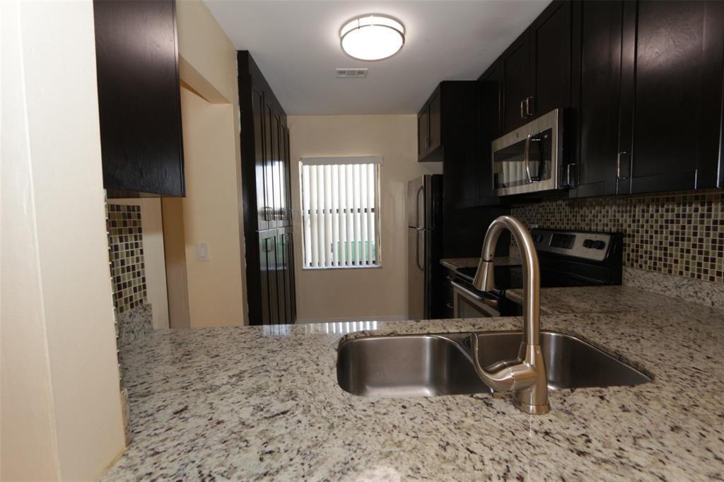 A kitchen features dark wood cabinets, granite countertops, a stainless steel sink, and tile backsplash — 2987 NW 110th Avenue, Sunrise FL 33322, SUNRISE, FL