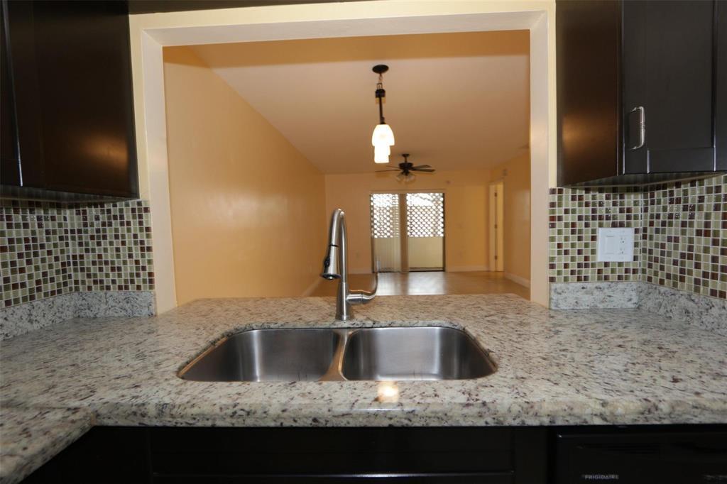 A kitchen sink with a granite countertop overlooks an open living area with sliding doors — 2987 NW 110th Avenue, Sunrise FL 33322, SUNRISE, FL