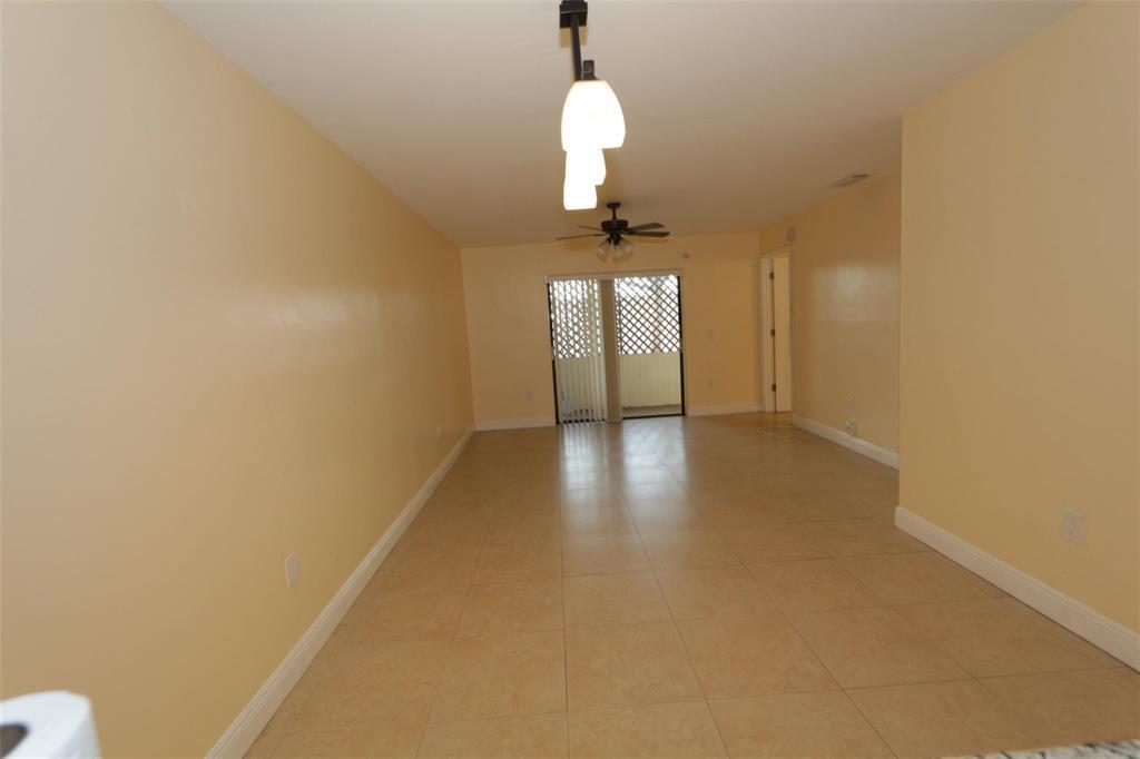 An empty living room with light-colored walls, tile flooring, a ceiling fan, and sliding doors — 2987 NW 110th Avenue, Sunrise FL 33322, SUNRISE, FL
