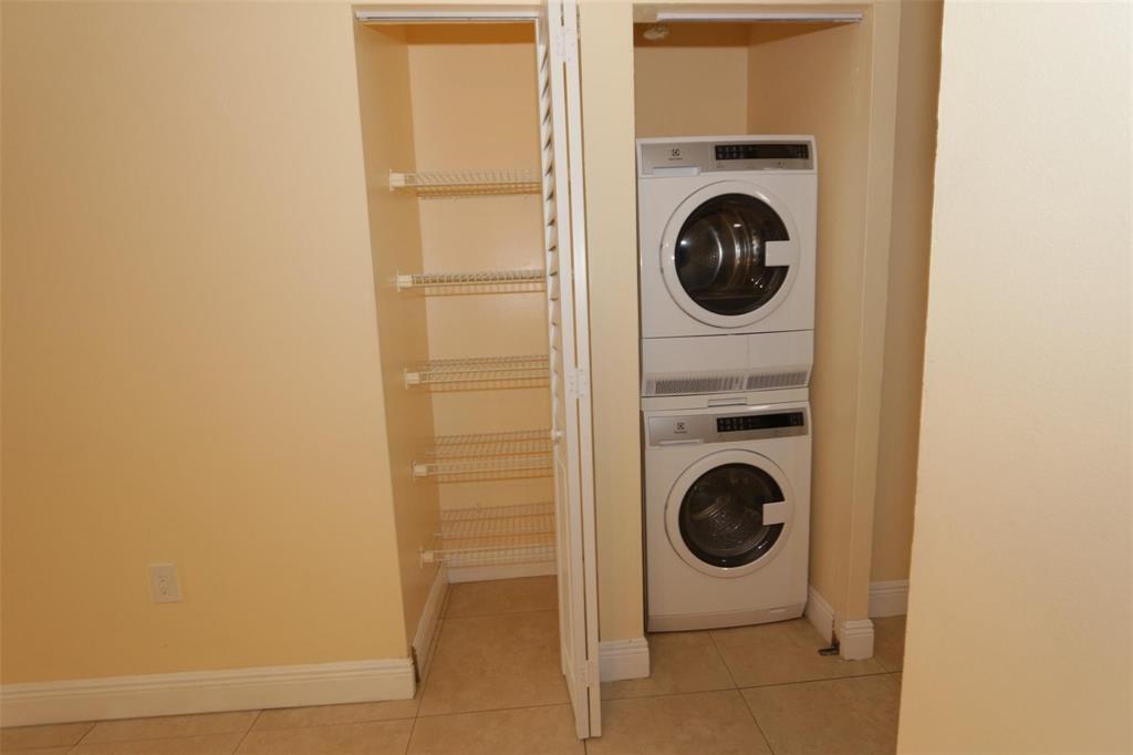 A laundry closet contains a stacked washer and dryer next to a built-in wire shelving unit — 2987 NW 110th Avenue, Sunrise FL 33322, SUNRISE, FL